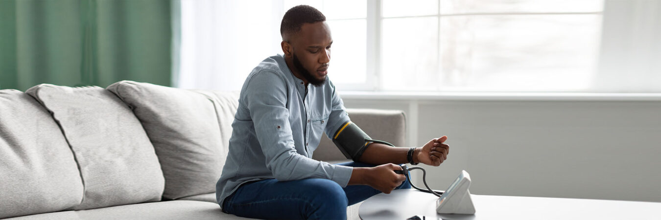 Man on couch taking blood pressure
