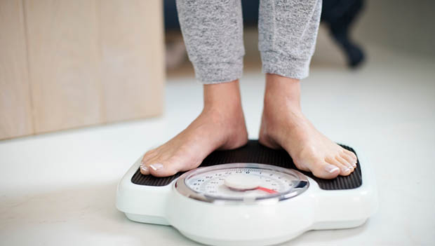 Woman Standing On Bathroom Scales